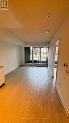 Toronto (Humber Heights) condo for rent - A spacious room with wooden flooring and a sliding glass door leading to a balcony.