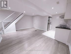 Toronto (The Beaches) apartment for rent - A spacious, empty room with a staircase on the left and a kitchen area on the right.