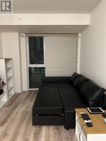 Waterloo condo for rent - A black leather sofa in a modern living room with a wooden table in front of it.