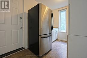 Hamilton (Corktown) duplex for rent - A black fridge in a white room with a door on the left.
