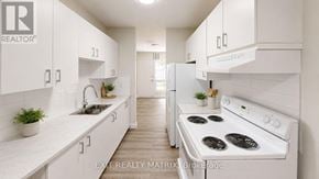Ottawa townhouse for rent - A white kitchen with a stove top oven and a sink.