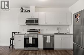 Lasalle condo for rent - A kitchen with white cabinets and a black stove top oven.