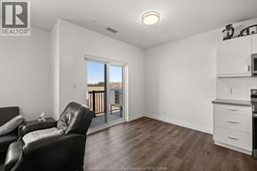 Lasalle condo for rent - A living room with a black leather chair and a kitchen area with white cabinets.