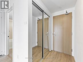 Toronto (Yorkdale-Glen Park) condo for rent - A white hallway with a wooden door and a mirror on the wall.
