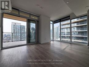 Toronto (Waterfront Communities) condo for rent - A real estate listing photo of a large, empty room with a view of the city.