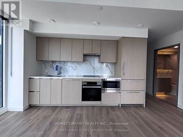 Toronto (Waterfront Communities) condo for rent - A modern kitchen with wooden cabinets and stainless steel appliances.