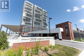 Oshawa (Windfields) condo for rent - A modern building with a sign that reads "Entrance to 2550 Simcoe Street N" in front of it.
