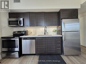 Toronto (Mimico) condo for rent - A modern kitchen with stainless steel appliances and dark wood cabinets.
