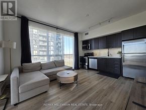 Toronto (Mimico) condo for rent - A modern living room with a large window and a kitchen area.