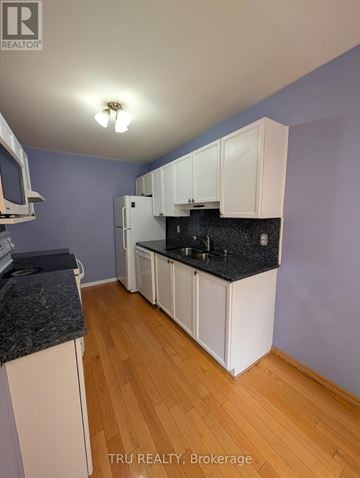 Ottawa townhouse for rent - A kitchen with white cabinets and a black countertop.