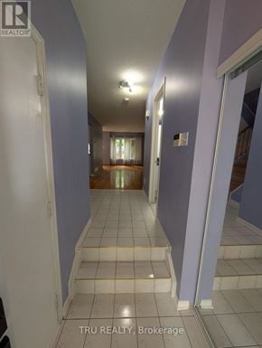 Ottawa townhouse for rent - A hallway with a white door on the left and a bedroom with a window and curtains on the right.