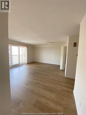 Windsor condo for rent - A large empty room with wooden flooring and a window.