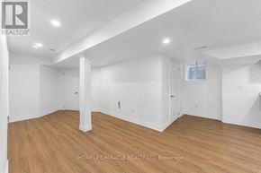 Oshawa (Taunton) apartment for rent - A spacious room with wooden flooring and white walls.