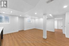 Oshawa (Taunton) apartment for rent - A spacious room with wooden flooring and white walls.