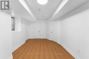 Oshawa (Taunton) apartment for rent - A room with wooden floors and white walls, with a logo in the top left corner that reads "REALTOR".