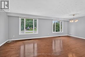 Hamilton (Fruitland) apartment for rent - A room with wooden floors and two windows showing trees outside.