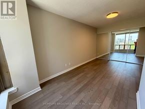 Toronto (Annex) condo for rent - A room with wooden flooring and a window overlooking a cityscape.