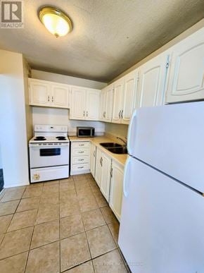 St. Catharines (Glendale/Glenridge) condo for rent - A kitchen with white appliances and cabinets.