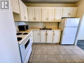 St. Catharines (Glendale/Glenridge) condo for rent - A kitchen with white cabinets and appliances.