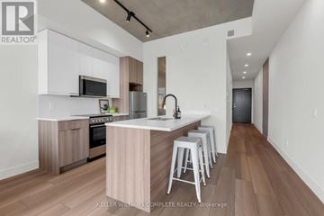 Hamilton (Corktown) condo for rent - A modern kitchen with white cabinets and a wooden island.