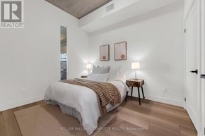 Hamilton (Corktown) condo for rent - A bedroom with a bed, a side table with a lamp, and two pictures on the wall.