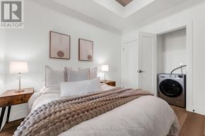 Hamilton (Corktown) condo for rent - A bedroom with a large bed and a washing machine in the corner.