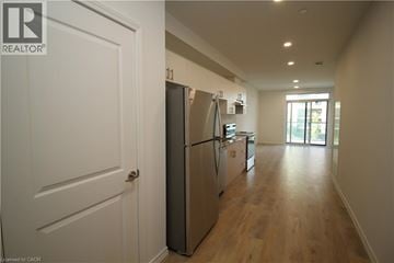 Guelph condo for rent - A white door is on the left of a kitchen with a refrigerator and a stove.