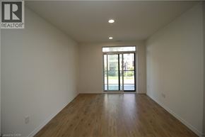 Guelph condo for rent - A large empty room with wooden floors and a sliding glass door.