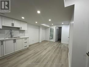 Clarington (Bowmanville) apartment for rent - A spacious kitchen with white cabinets and a wooden floor.