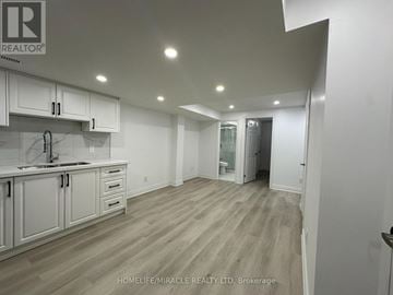 Clarington (Bowmanville) apartment for rent - A spacious kitchen with white cabinets and a wooden floor.