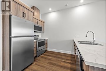 Charlottetown condo for rent - A modern kitchen with a stainless steel refrigerator and wooden cabinets.