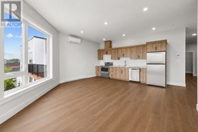 Charlottetown condo for rent - A large empty room with wooden floors and a kitchen area in the background.