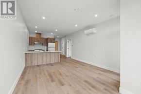 Charlottetown condo for rent - A spacious room with wooden flooring and a kitchenette area.