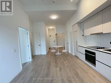 Toronto (Dovercourt-Wallace Emerson-Junction) condo for rent - A spacious kitchen with white cabinets and a wooden floor.