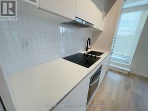 Toronto (Dovercourt-Wallace Emerson-Junction) condo for rent - A kitchen with white cabinets and a black countertop.