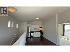 Coquitlam apartment for rent - A spacious kitchen with white cabinets and appliances, and a large window on the right side.