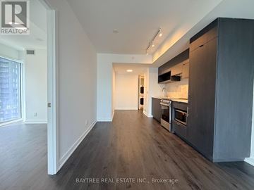 Toronto (Church-Yonge Corridor) condo for rent - A spacious kitchen with dark wood cabinets and a white wall.