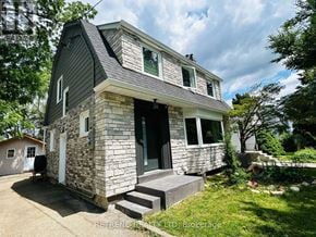 Toronto (Lansing-Westgate) apartment for rent - A house with a stone facade and a grey roof is surrounded by greenery.