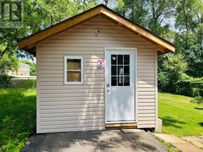 Toronto (Lansing-Westgate) apartment for rent - A small house with a white door is surrounded by greenery.