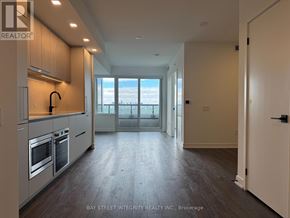 Toronto (North St. James Town) condo for rent - A spacious kitchen with wooden floors and a view of the city through the window.