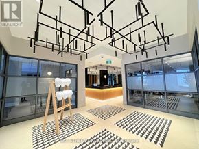 Oshawa (Windfields) condo for rent - A modern office lobby with a wooden stool and black and white patterned mats.