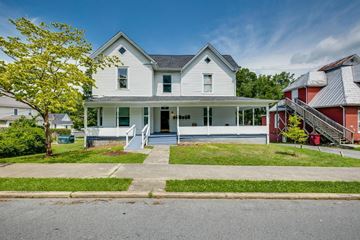 Johnson City apartment for rent - A white two-story house with a grey roof and a red house in the background.