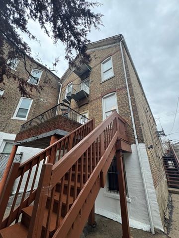 Chicago apartment for rent - A brown wooden staircase leads up to a brick building.