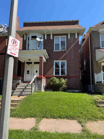 Saint Louis apartment for rent - A red brick house with a white door and a sign on a pole in front of it.