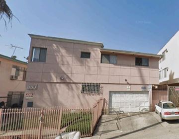 Los Angeles apartment for rent - A pink building with a white garage door and a car parked in front.