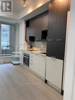 Toronto (Waterfront Communities) condo for rent - A modern kitchen with white cabinets and a wooden floor.