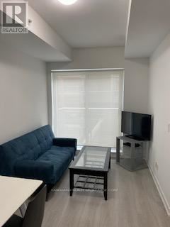 Toronto (Waterfront Communities) condo for rent - A living room with a blue couch and a television.
