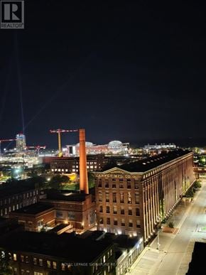 Toronto (South Parkdale) condo for rent - A nighttime cityscape with a large building in the foreground.