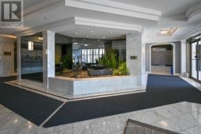 Toronto (Kennedy Park) condo for rent - A lobby with a large planter in the middle and a carpet on the floor.