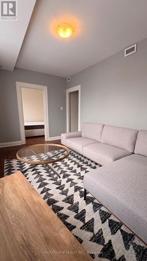 Oshawa (O'neill) apartment for rent - A living room with a white couch and a black and white rug.
